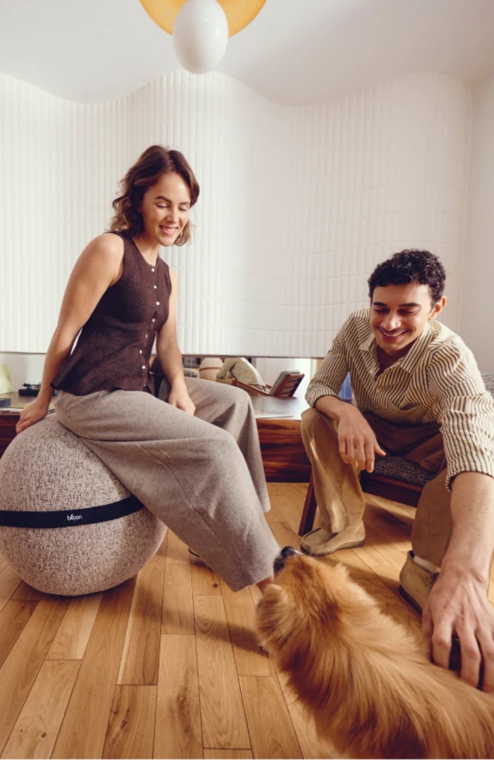 Femme assise sur un ballon Bloon à côté d'un homme caressant un chien